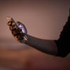 A close-up of a hand holding a mobile phone as the light shines from the phone screen