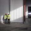 Two male Stena Recycling employees in protective gear look at a mobile phone together in a recycling facility